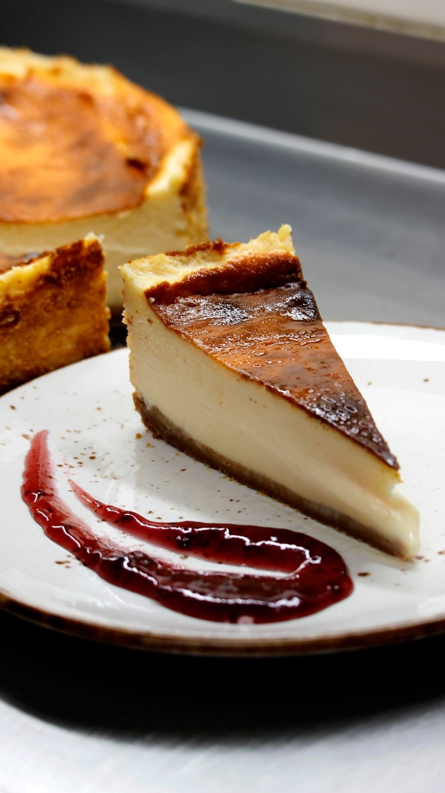 A slice of Basque burnt cheesecake with berry sauce