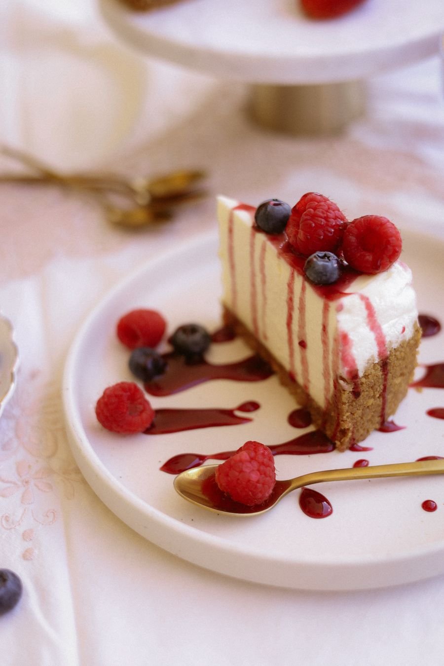 A slice of no-bake cheesecake with berries and berry sauce